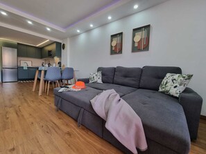 A modern living room with a grey sofa, a dining table, and chairs. There are two framed artworks on the wall. - Casa Liotro Panoramic AND Central TWO Bedrooms (Los Cristianos)