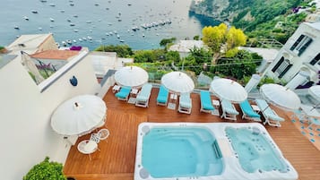 Una piscina al aire libre, sombrillas, sillones reclinables de piscina