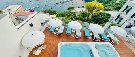 Una piscina al aire libre, sombrillas, sillones reclinables de piscina