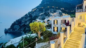 A coastal building with a staircase leading to a balcony overlooking the sea.