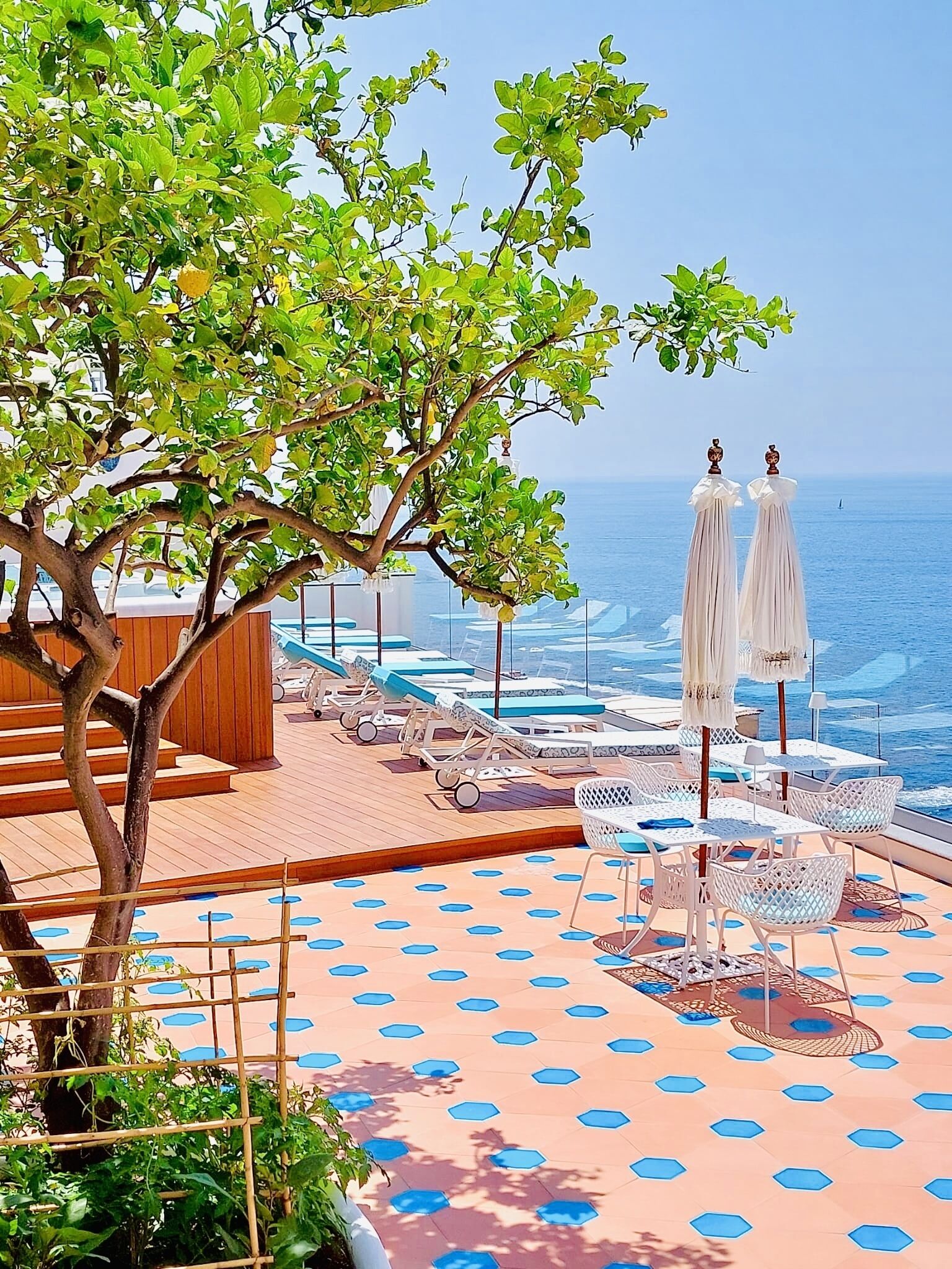 A sun deck with lounge chairs and umbrellas overlooking the ocean.
