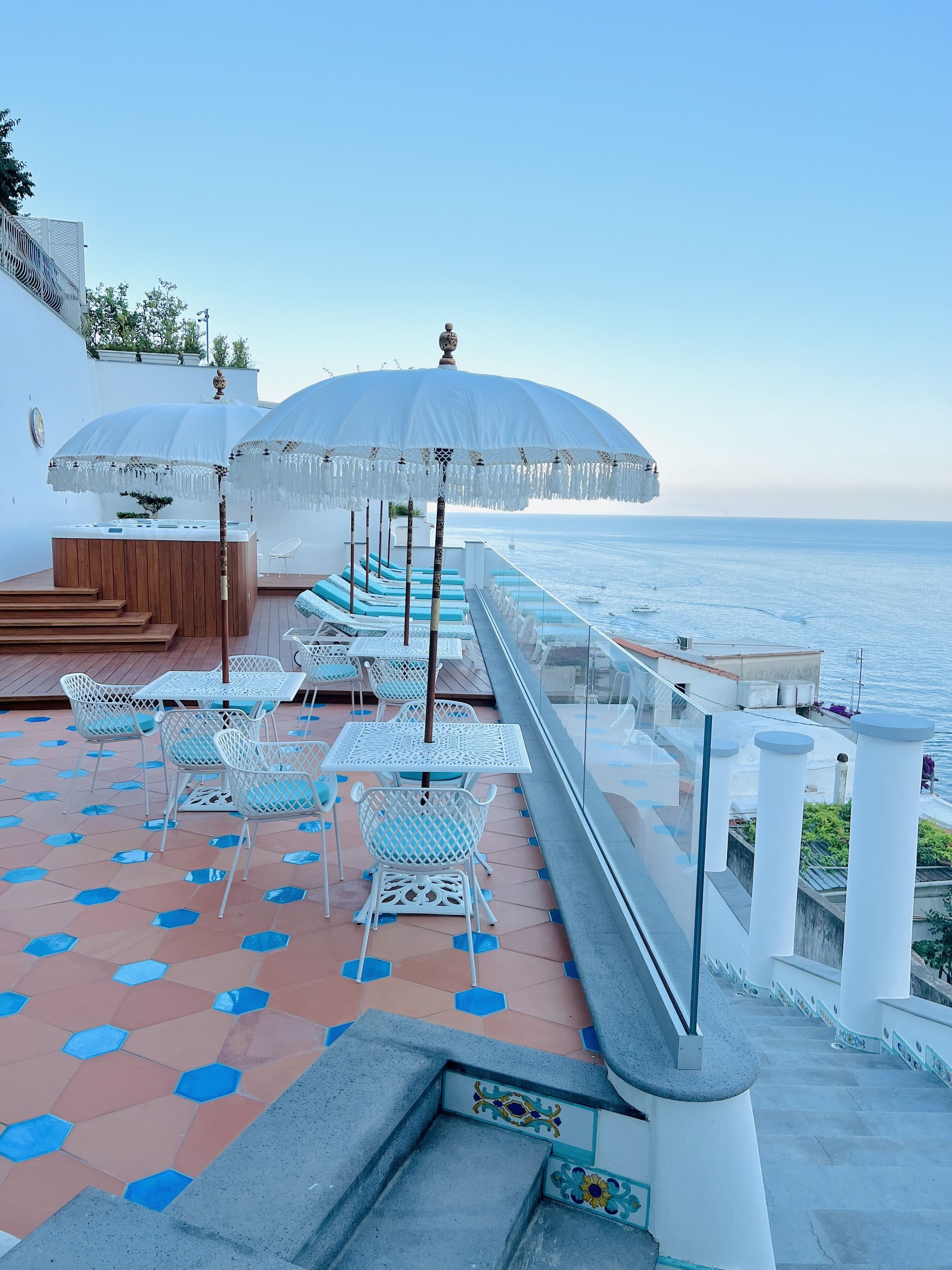 A rooftop terrace with outdoor seating, a hot tub, and a view of the sea.