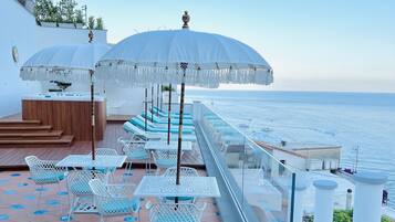 A rooftop terrace with outdoor seating, a hot tub, and a view of the sea.