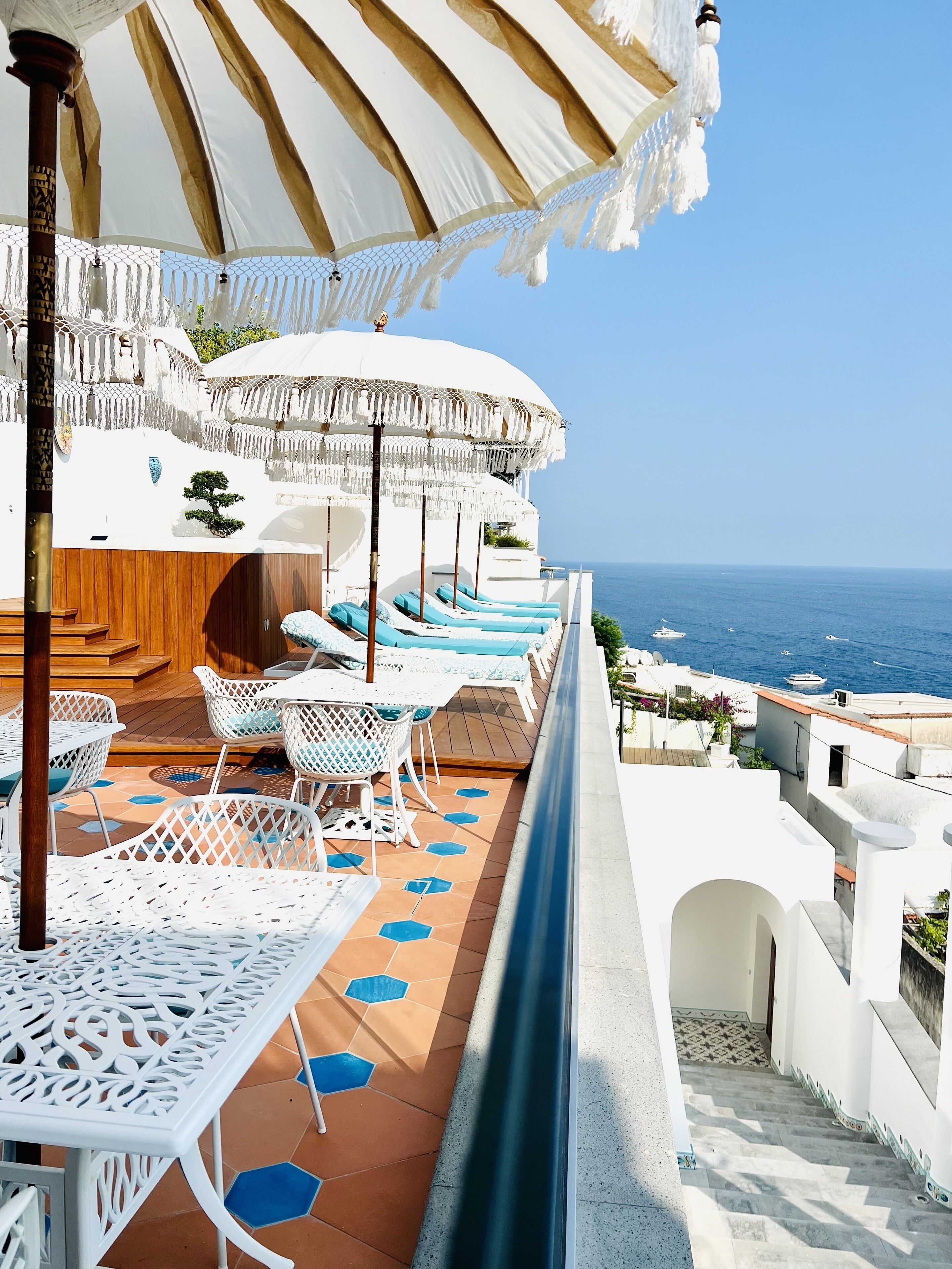Une terrasse dotée de mobilier d’extérieur blanc, une piscine et une vue sur la mer.