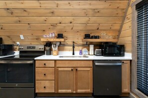 Una cocina compacta con armarios de madera, estufa de acero inoxidable, microondas y lavavajillas.