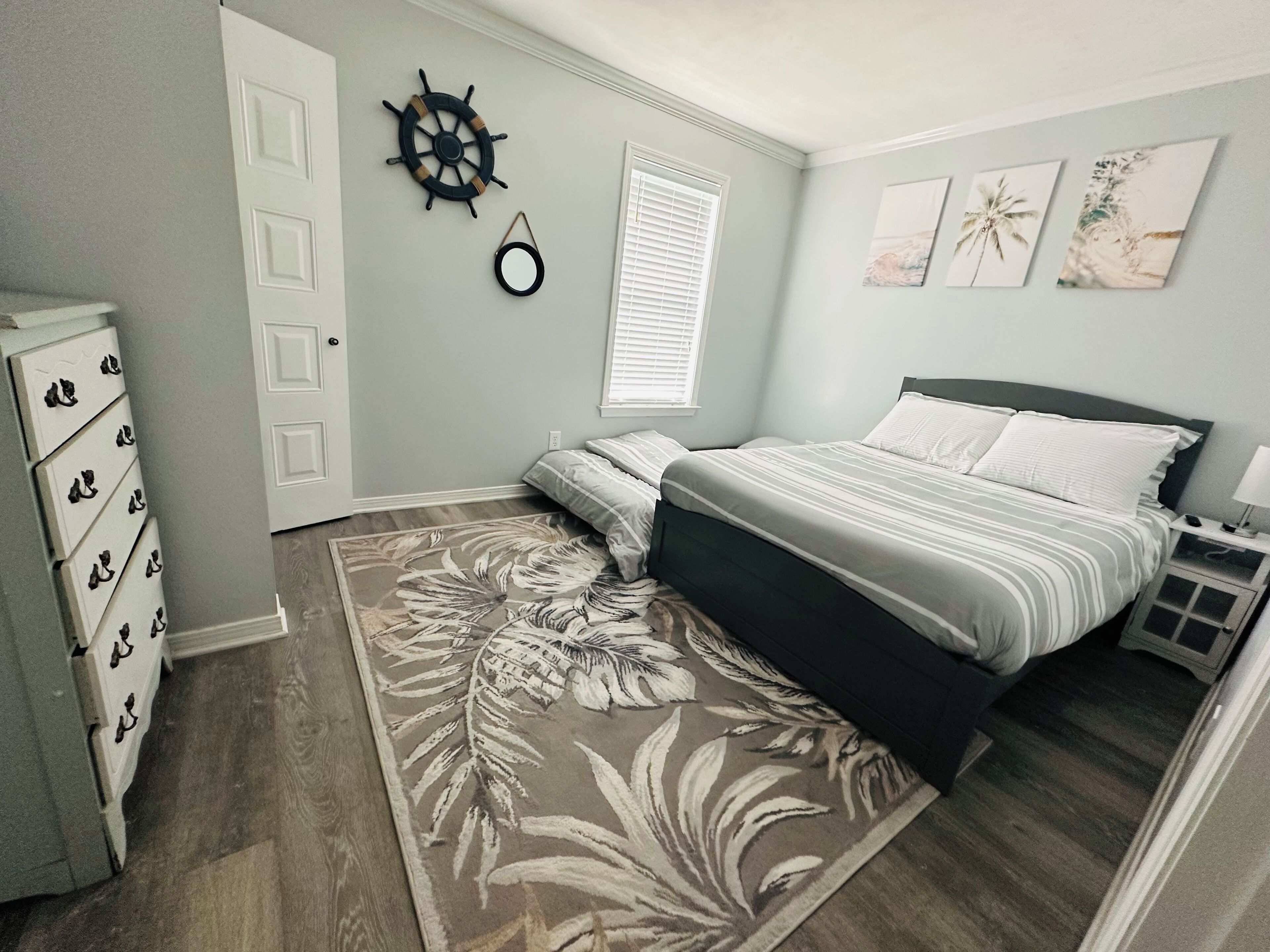 Un dormitorio con cama, cómoda y un adorno en la pared.