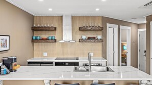 Een moderne keuken met een centraal eiland, inbouwplanken en een wandlamp.