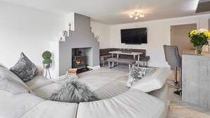 A modern living room with a fireplace, a dining area, and a kitchen. - Host & Stay | Casa Feliz (Skirlaugh)