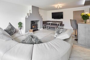 A modern living room with a fireplace, a dining area, and a kitchen. - Host & Stay | Casa Feliz (Skirlaugh)