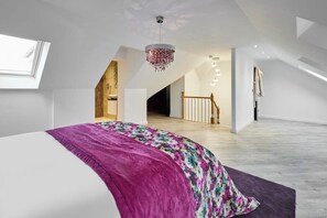 A modern bedroom with a large bed, a purple throw, and a chandelier. - Host & Stay | Casa Feliz (Skirlaugh)