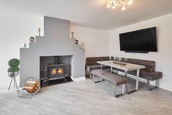 A modern living room with a fireplace, a sofa, a table with glasses, and a TV mounted on the wall.