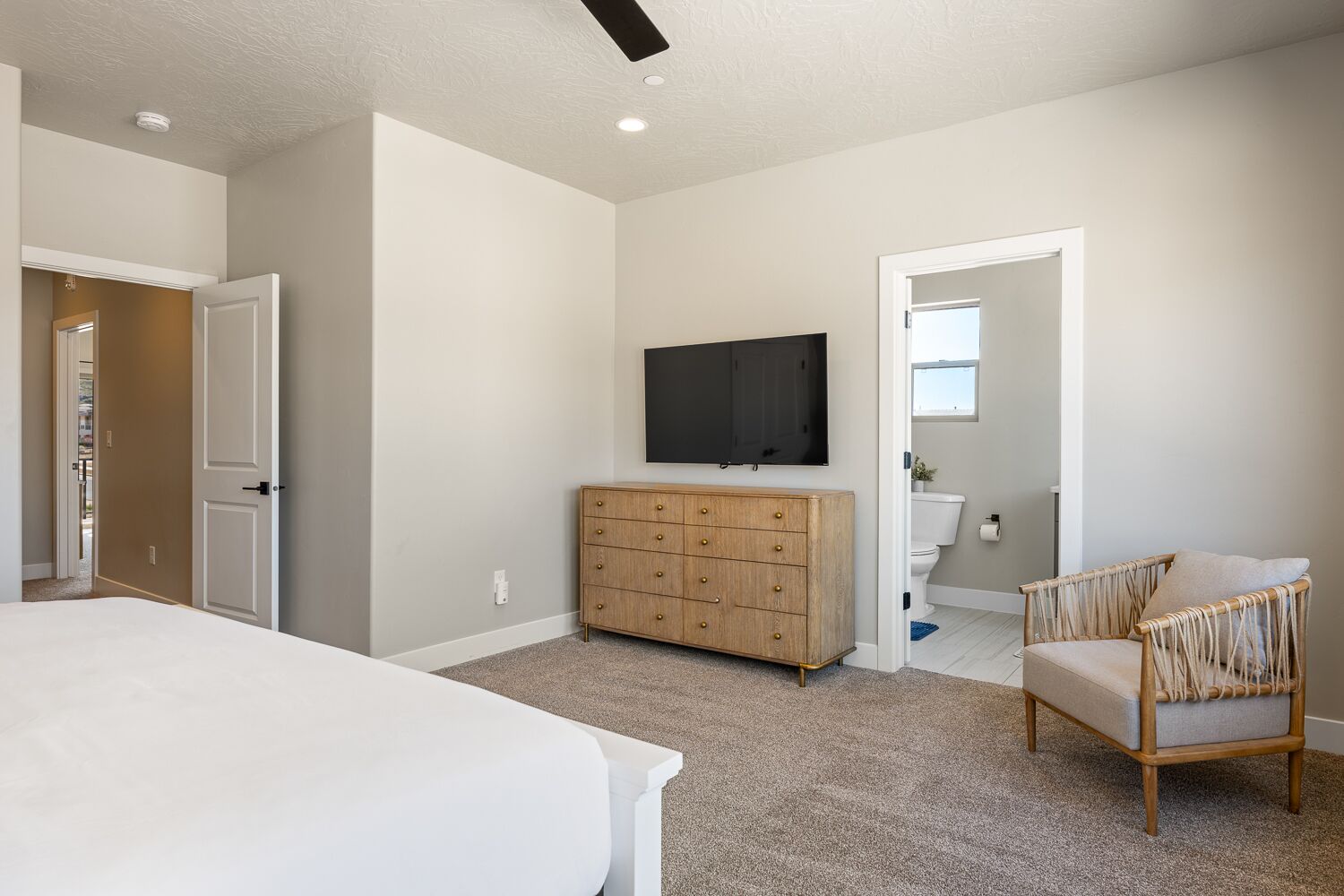 A bedroom with a bed, a dresser, a TV, and a chair.