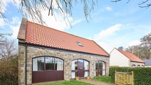A stone house with a red-tiled roof, large windows, and a paved driveway. - Host & Stay | The Coach House (Beal)