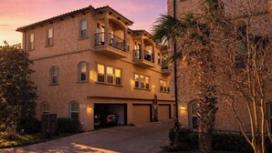 Un edificio residencial de varios pisos con entrada para vehículos, garaje y un balcón en el nivel superior.