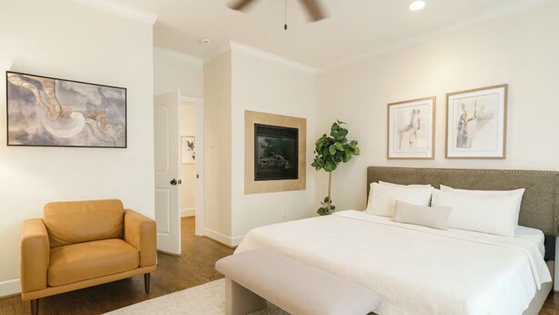A bedroom with a bed, a bench, a chair, and artwork on the walls.