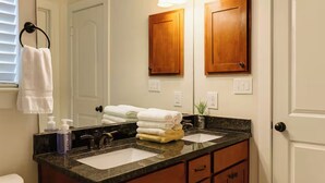 A bathroom with two sinks, wooden cabinets, a towel rack, and a mirror.