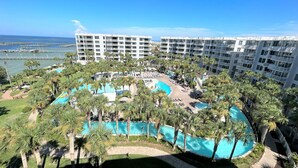 A resort with multiple swimming pools surrounded by palm trees, a marina in the background, and high-rise buildings. - DestinWest 3Bd Amenities Galore Free Beach Service (Fort Walton Beach)
