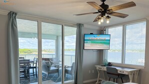 A hotel room with a large sliding glass door leading to a balcony with outdoor seating and a view of the ocean. - DestinWest 3Bd Amenities Galore Free Beach Service (Fort Walton Beach)