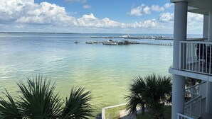 A view of a marina with boats docked, a clear sky, and a building with balconies overlooking the water. - DestinWest 3Bd Amenities Galore Free Beach Service (Fort Walton Beach)