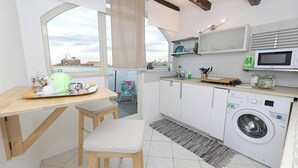 A compact kitchen with a washing machine, a microwave, and a dining area with a view. - Terrace In The Historic Center In Palermo Rosa (Palermo)