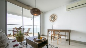 A modern living room with a view of the sea, a dining area with a table and chairs, and a large mirror on the wall. - Palmetto Beach 1402 & Sea View - Hot Water- 2bth (Cartagena)
