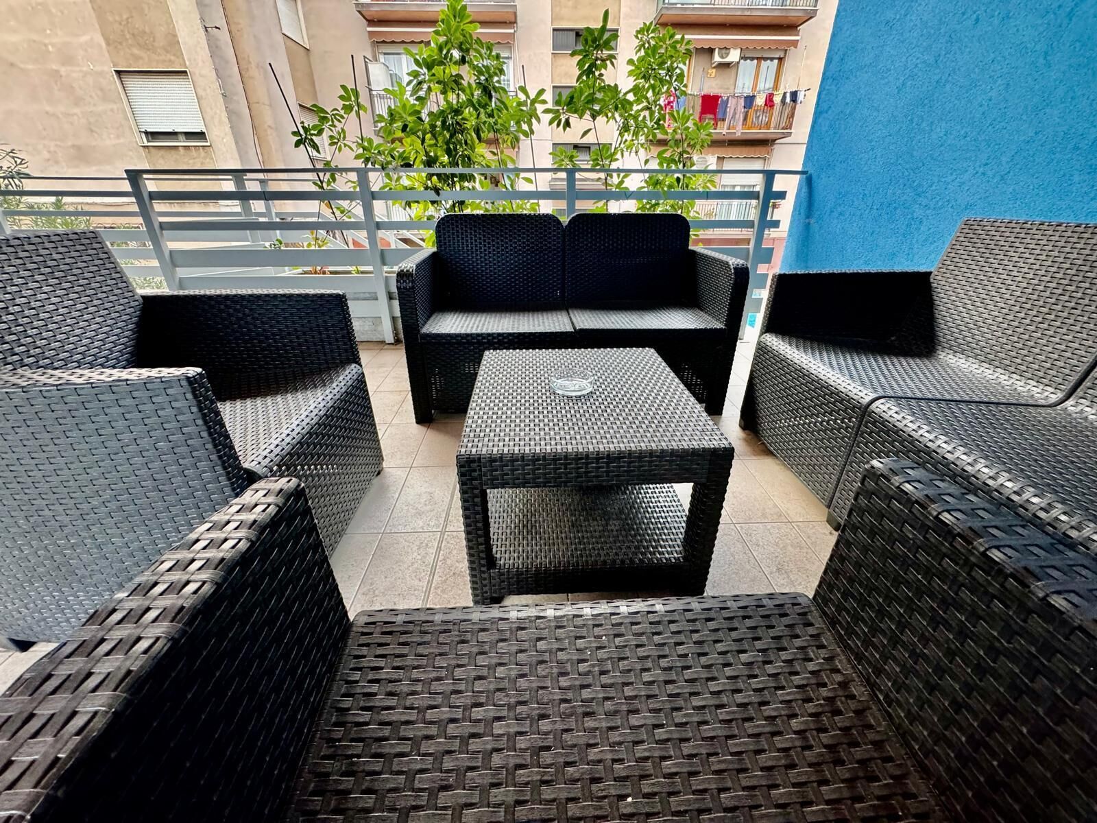 A balcony with wicker furniture, including a sofa and two chairs, and a small table.