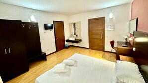 A hotel room with a bed, a desk, a chair, a wardrobe, a TV, a mirror, and a bathroom with a sink and toilet. - Hotel Guidi (Mestre)