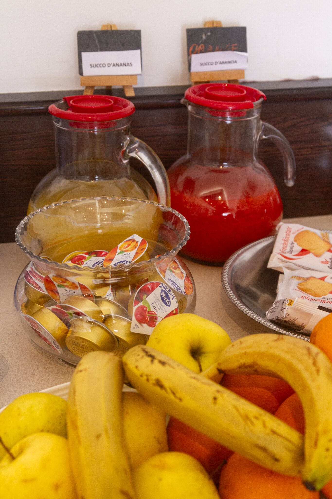 A table with two pitchers, a bowl of fruit, and a tray with food packets.