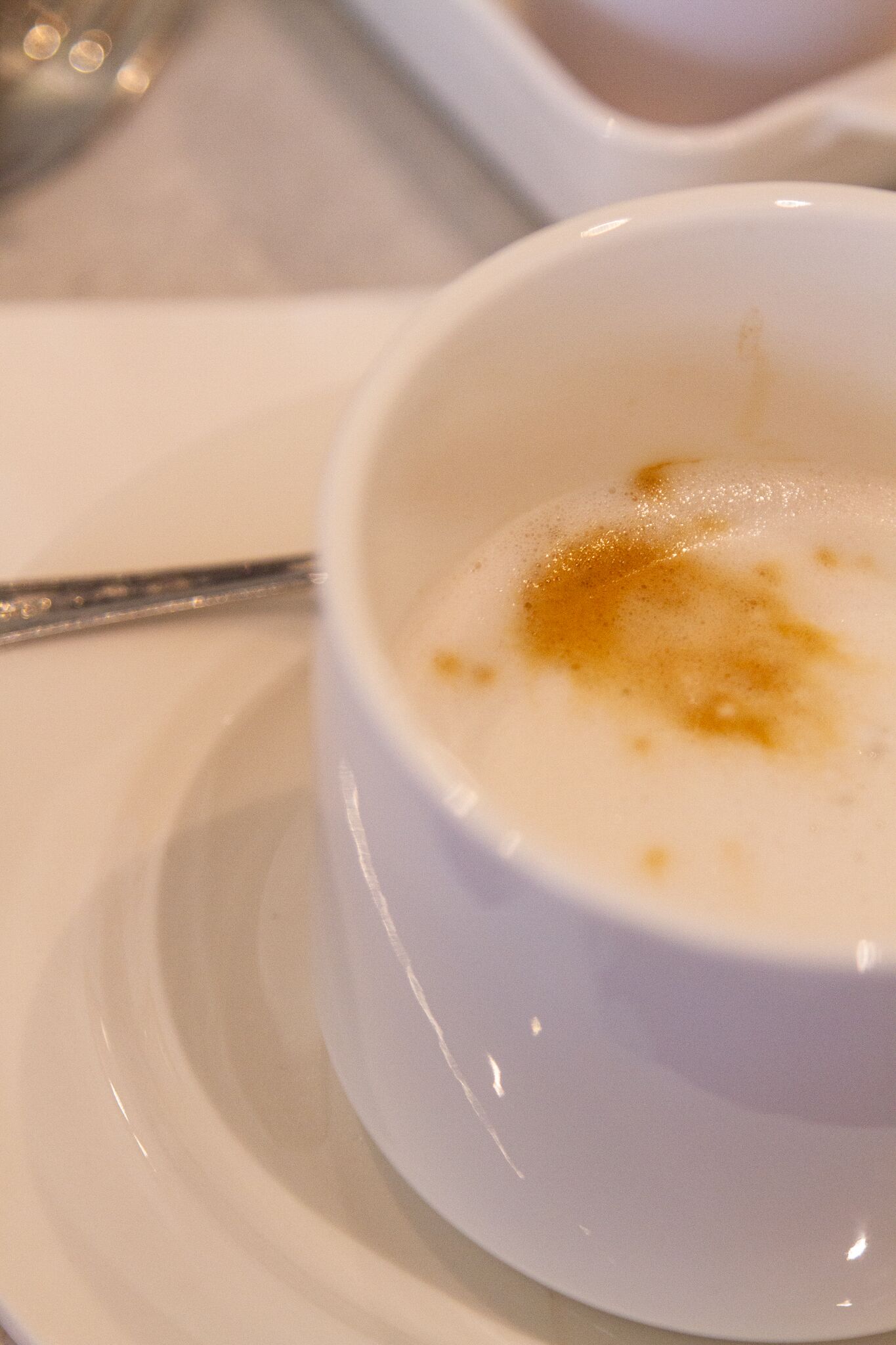 Un bol blanco con una sustancia cremosa, posiblemente un postre, sobre un plato blanco.
