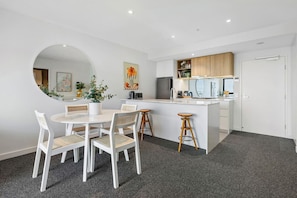 A modern kitchen with white cabinets, a central island, and a round mirror.