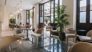 A modern interior with round tables, chairs, and a large mirror. -  MASANET Emblematic Hotels by Airnest (Las Palmas de Gran Canaria)