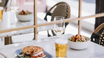 Een eettafel met een boterham, een saladeschaal en een glas bier.
