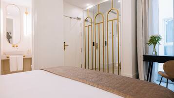 A modern hotel room with a large bed, a vanity with a mirror, and a walk-in closet with a mirror.