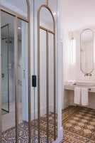 Un bagno moderno con cabina doccia in vetro, una vasca da bagno indipendente e un pavimento decorato.
