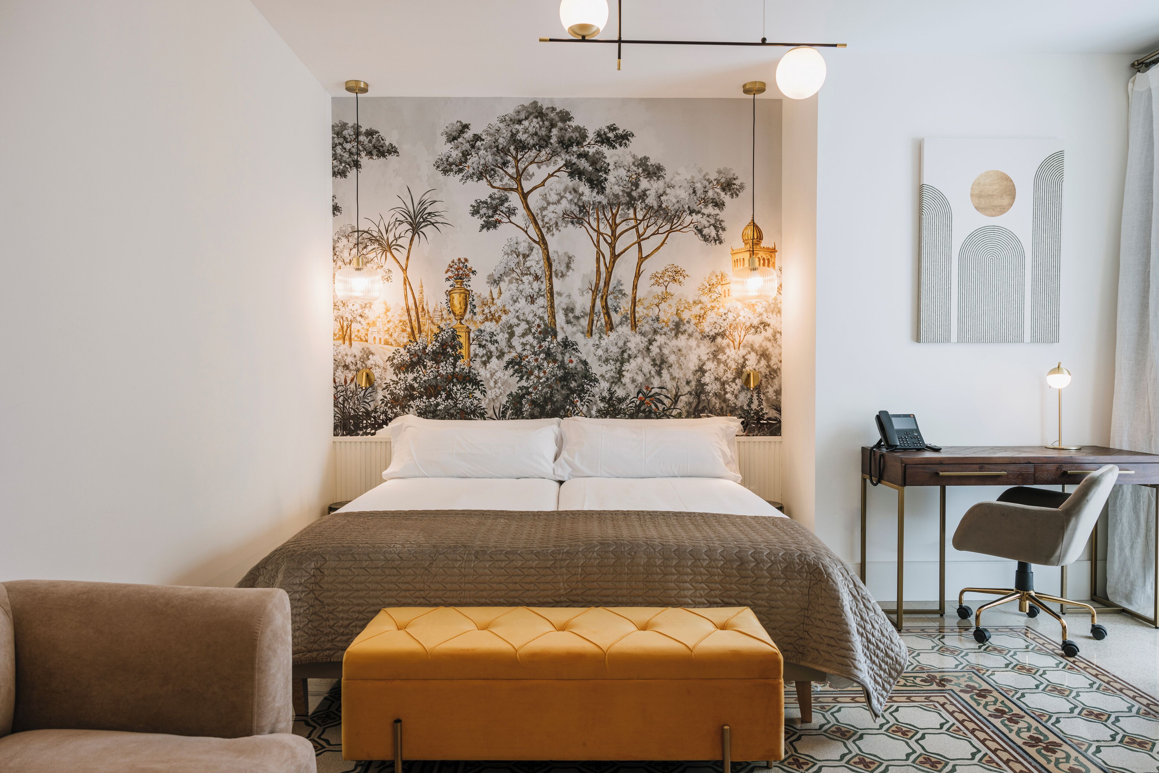 A bedroom with a bed, a desk, a chair, and a wall with a mural.