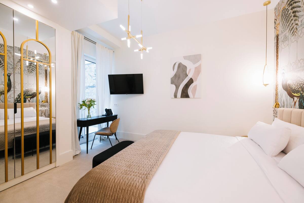 Une chambre moderne avec un grand lit, un bureau, une télévision et un miroir.
