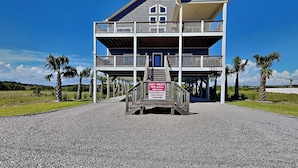 A two-story building with a balcony and a sign indicating it is 580 miles from New York City. - Family Tides | Spacious Oceanfront Home, Sound Views + Hot Tub! (North Topsail Beach)