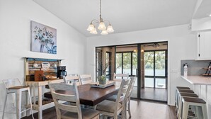 A dining area with a wooden table and chairs, a coffee station, and a view through a glass door. - Twilight Lodge on Diamond Lake - Waterfront Home (Horseshoe Bend)