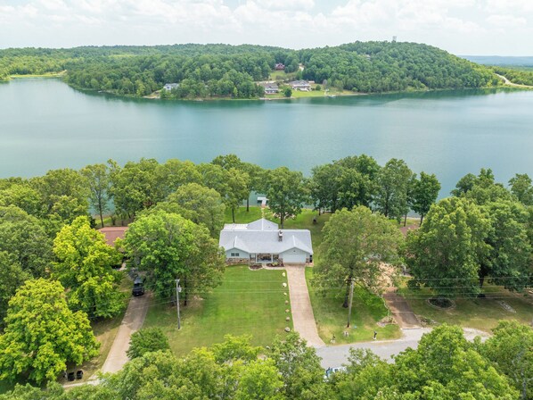 A large house with a spacious lawn and a view of a lake.