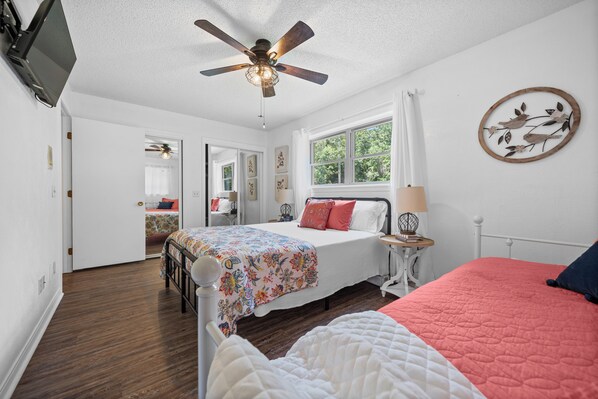 Une chambre à coucher avec un lit, un ventilateur de plafond, une fenêtre et un élément décoratif mural.