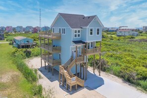 A two-story house with a wooden deck and a staircase leading to the upper floor.