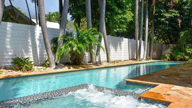 A swimming pool with a hot tub, surrounded by palm trees and a white fence. - Fort Lauderdale Oasis w/ Pool ~ 2 Mi to Beach! (Fort Lauderdale)