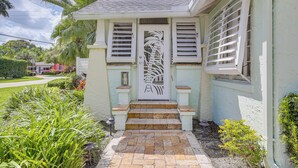 A house with a white exterior, a front door with a decorative palm tree design, and a small porch with steps leading to the door. - Fort Lauderdale Oasis w/ Pool ~ 2 Mi to Beach! (Fort Lauderdale)