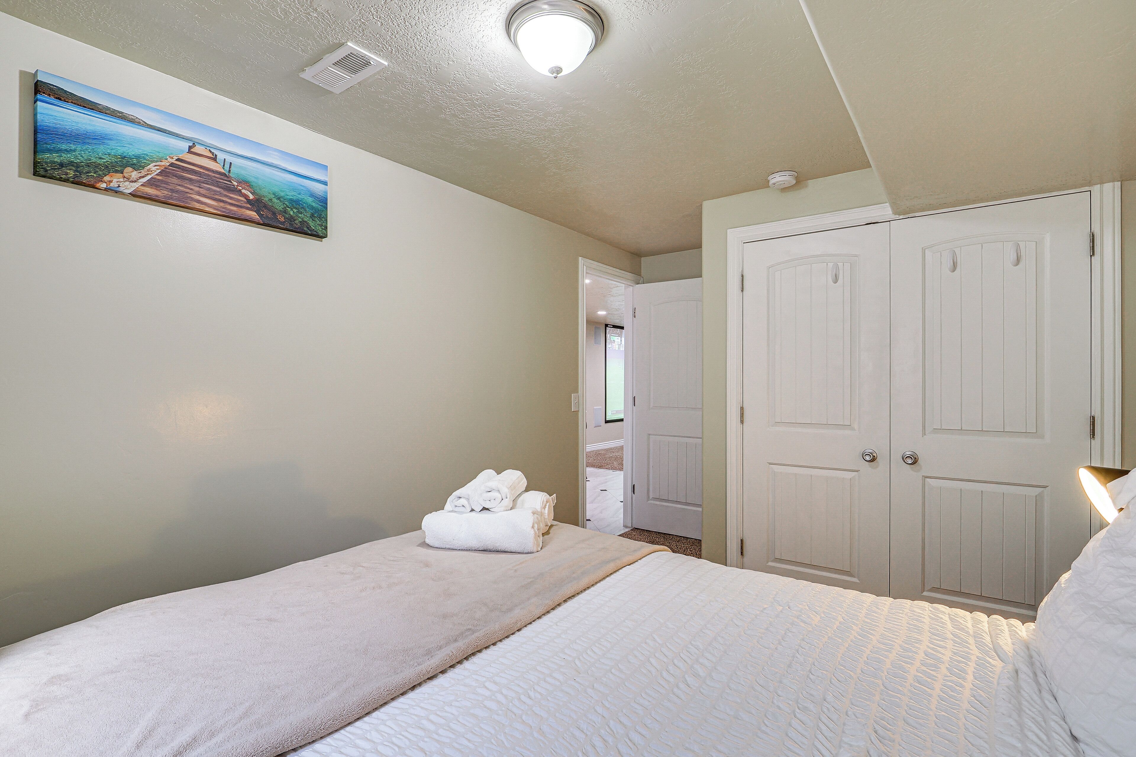 A bedroom with a bed, a painting, and a closet.