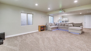A living room with a sectional sofa, a fireplace, and a ceiling projector.