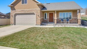 A two-story house with a garage, a front porch with chairs, and a well-maintained lawn.