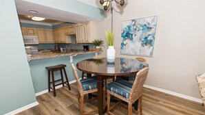 A dining area with a round table, wicker chairs, and a vase on the table.