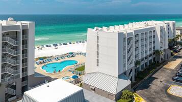 A hotel with a pool, beach, and ocean view.