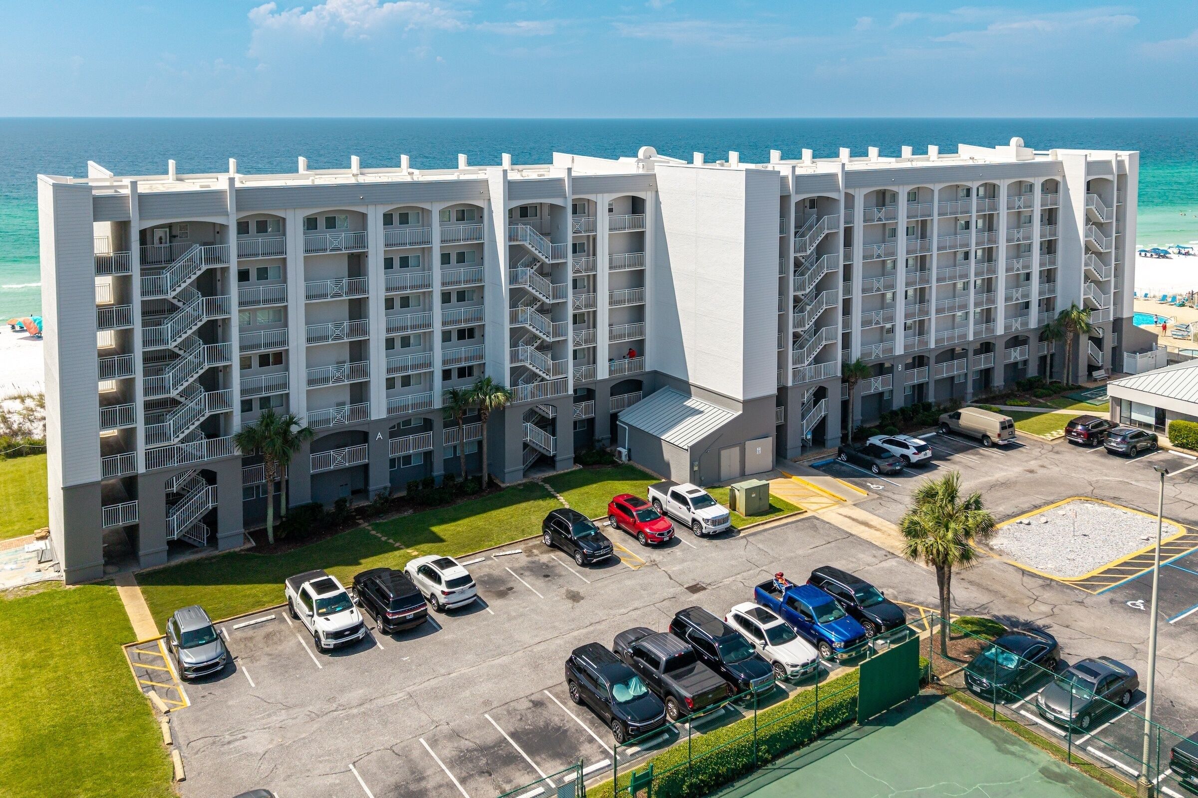 Een meerhoog hotel met een parkeerplaats en uitzicht op het strand.