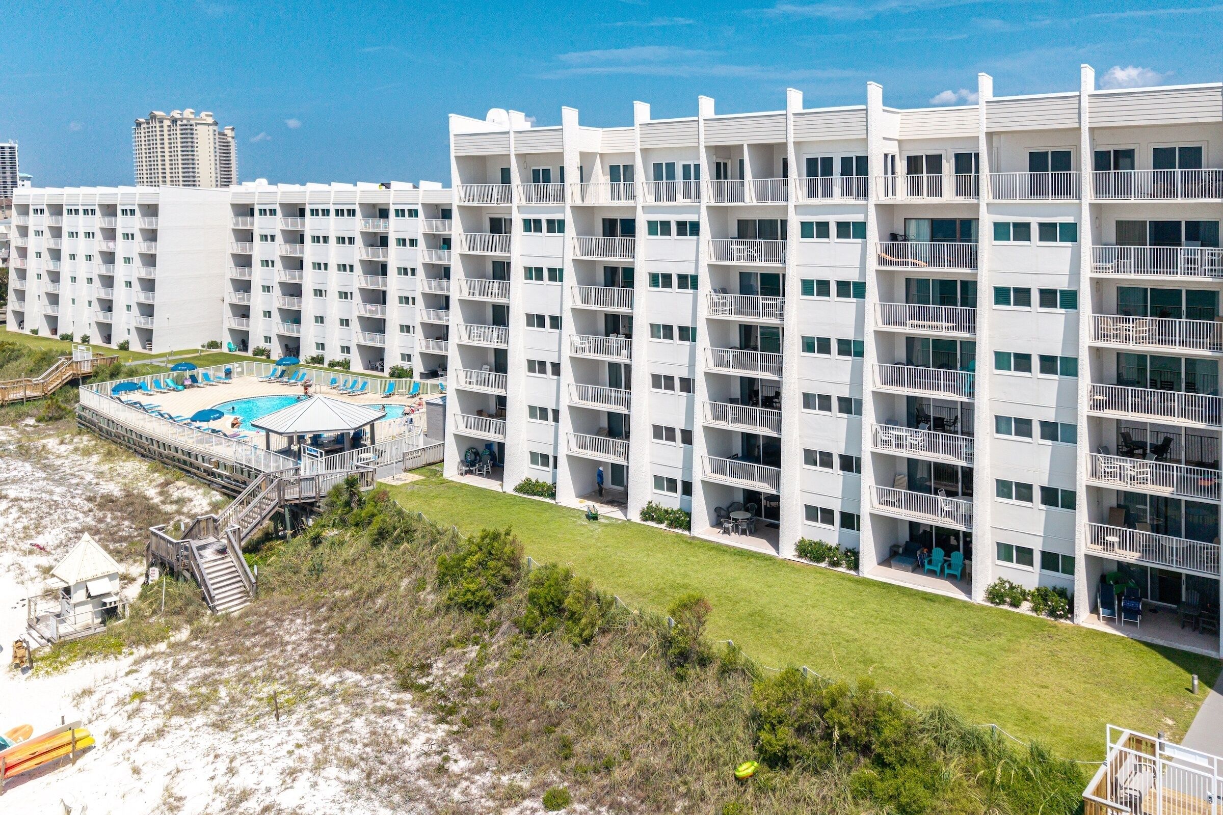 Un hotel de varios pisos con balcones, piscina y zona de playa.